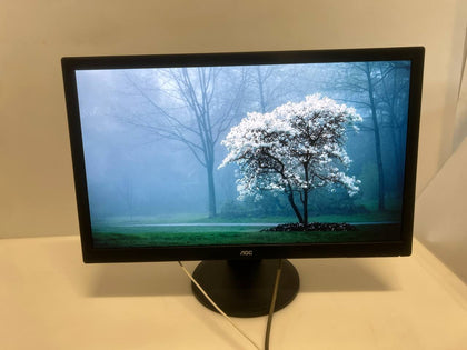 Monitor displaying a scenic wallpaper of a tree with white flowers on a grassy field.